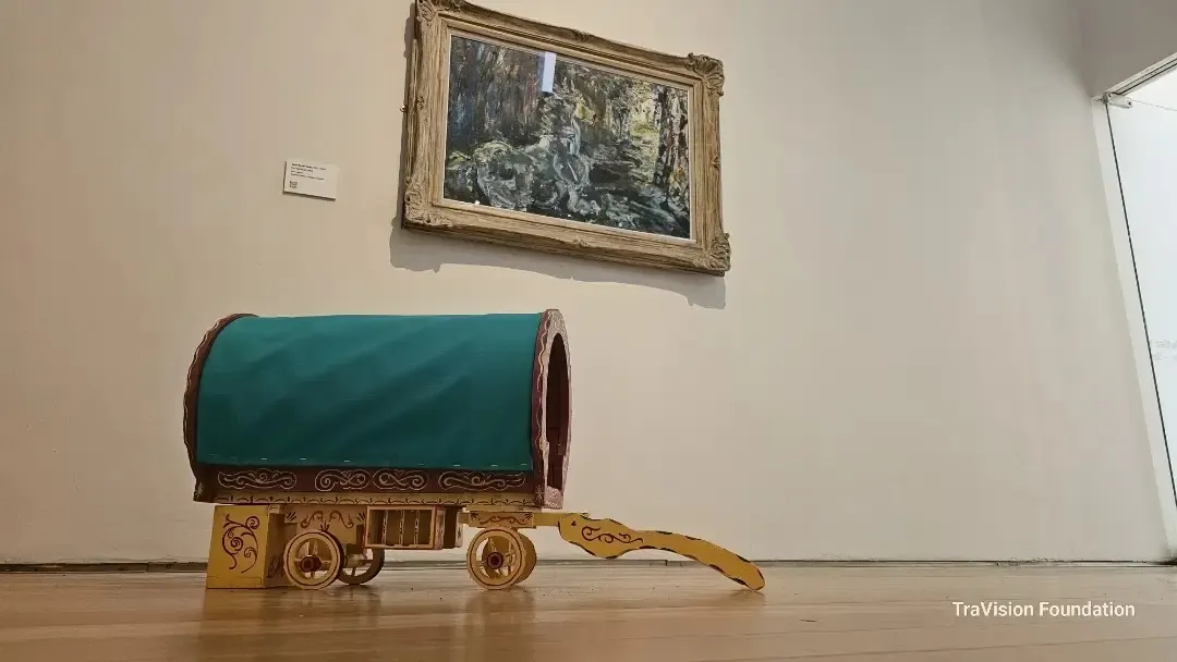 A small painted wagon model displayed beneath framed artwork.